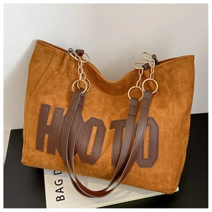 Macro shot of brown suede tote bag featuring large HOOTO letter patch and metal chain strap