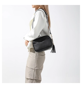 Detail of black pebbled leather crossbody bag with fringe tassel and woven chain strap