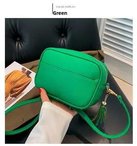 Detail view of emerald green crossbody bag with pebbled PU leather and decorative fringe
