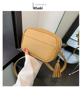 Detail of khaki pebbled leather camera bag featuring a decorative tassel and zipper closure