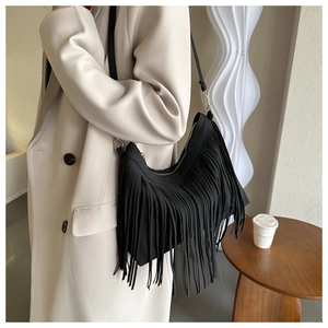 Detail of black fringe hobo shoulder bag showing tassel texture and crossbody style