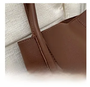 Close-up of durable stitching and premium litchi grain leather on a brown tote bag
