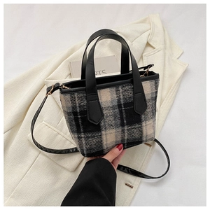 Detail of checkered tweed tote bag with black leather handles and shoulder strap