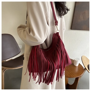 Detail of burgundy hobo bag featuring long flowing fringes and adjustable shoulder strap