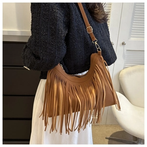Detailed view of brown fringe shoulder bag with long tassels and adjustable strap on model
