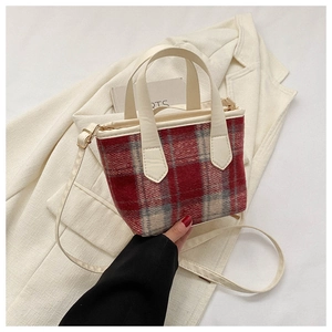 Detail of red and cream plaid tote bag with faux leather handles and strap