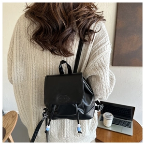 Mini sac à dos en cuir noir avec cordon de serrage et logo mode sur une tenue décontractée