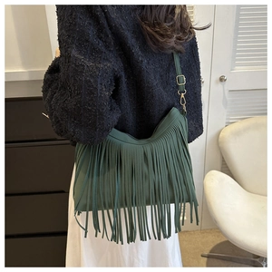 Detailed view of dark green tassel shoulder bag with adjustable strap on a female model