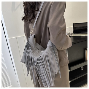 Detailed back view of a grey fringe shoulder bag on a model wearing a brown blazer