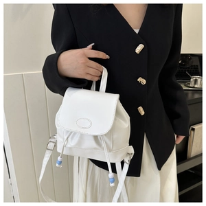 Gros plan d'un mini sac à dos blanc avec logo embossé et détails de cordon perlé
