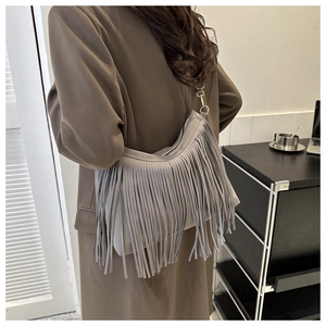Detail of grey bohemian fringe crossbody bag with suede finish and tiered tassels