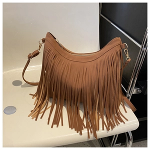 Close-up of brown suede shoulder bag featuring long fringe and gold-tone hardware