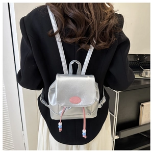 Détail du mini sac à dos argenté métallisé avec étiquette rose et cordon perlé