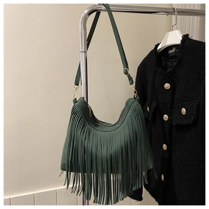 Detail shot of forest green tassel shoulder bag featuring golden metallic buckles and fringe