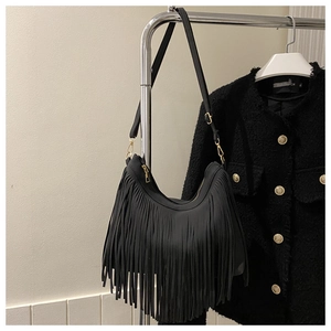 Close-up of black hobo bag featuring long tassels and gold-tone metal zipper hardware