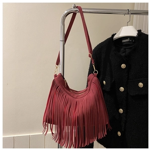 Detail of burgundy tassel handbag with suede finish and gold metal hardware accents
