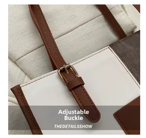 Detail of adjustable brown leather shoulder strap with bronze metal buckle on tote bag