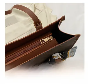 Close-up of contrast color tote bag showing the smooth metal zipper and silk scarf handle