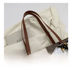 Detail of color-block tote bag with brown leather handle and floral silk scarf accessory