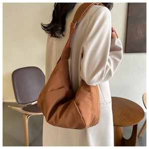 Sac à bandoulière plissé caramel en forme de croissant porté par un mannequin