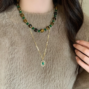 Vintage layered necklace with tiger eye beads and golden pendant on brown sweater