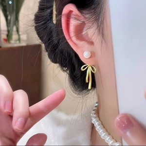 Boucles d'oreilles nœud doré avec perles portées pour un style délicat et raffiné