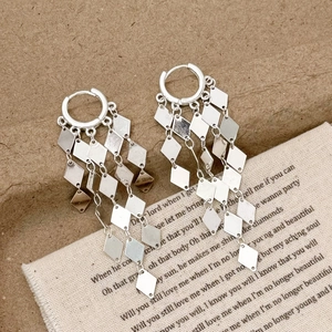 Macro detail of silver long tassel drop earrings with sparkling diamond-shaped metal sequins