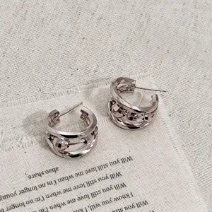 Macro detail of silver layered C-shaped hoop earrings with geometric metal beads