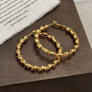 Detail of gold-plated hoop earrings with unique irregular twisted thorn texture on wood