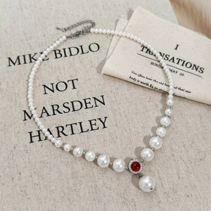 Vintage pearl necklace with red zircon pendant and silver beads on artistic canvas background