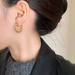 Elegant gold beaded geometric hoop earrings for women shown on a model's ear