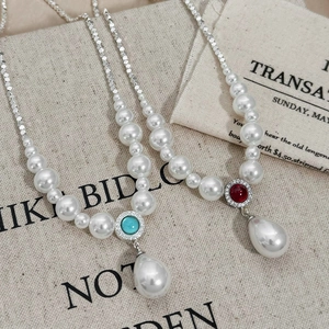 Detail of vintage pearl necklaces with red and turquoise stones and drop pendants
