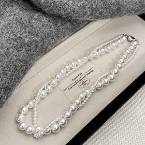 Collier double couche classique avec perles blanches présenté sur un écrin à bijoux