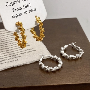 Elegant gold and silver textured hoop earrings with a spiral glitter finish on a wood surface