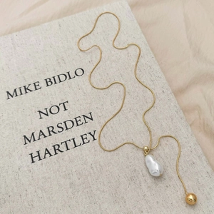Elegante goldene Schlangenkette mit Barockperlen-Anhänger auf einem Buch