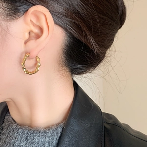 Minimalist vintage golden twisted hoop earrings with textured finish on model