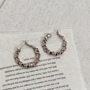 Macro shot of minimalist metal hoop earrings with a vintage twisted weave texture