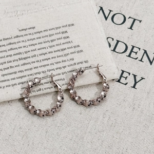 Minimalist gold hoop earrings with retro twisted design on textured linen background