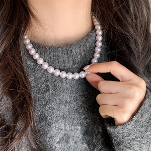 Detail of elegant lavender purple pearl necklace on grey sweater showing luster