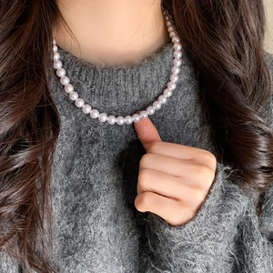 Detail of elegant lavender pearl necklace styled on a soft grey knitted sweater