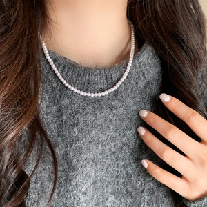 Elegant purple pearl necklace on grey sweater featuring round freshwater pearls