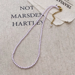 Detail of lavender pearl necklace with gold lobster clasp and extension chain on linen