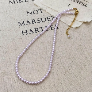Detail of lavender pearl necklace with gold clasp on rustic linen background