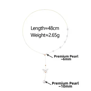 Détail du collier en chaîne dorée avec gland de perles et pendentif papillon