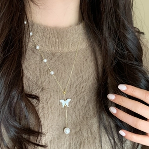 Collier élégant en chaîne dorée avec pendentif papillon blanc et pompons en perles