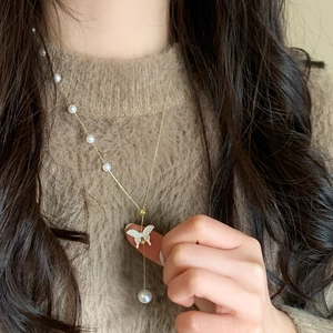 Élégant collier papillon doré avec petites perles et pendentif nacre sur modèle