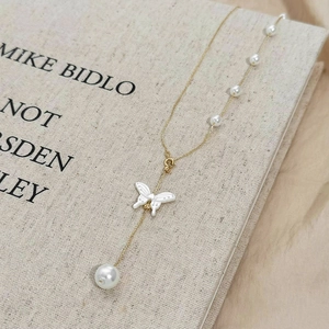 Collier papillon doré élégant avec perles délicates et pendentif pompon détaillé