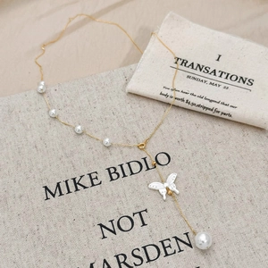 Détail du pendentif papillon doré avec des perles élégantes sur une chaîne fine