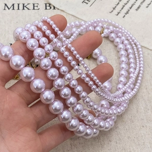 Elegant lavender pearl necklace in various sizes shown held in hand against fabric