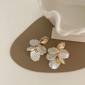Close-up of petal-shaped zircon earrings with white mother-of-pearl texture petals